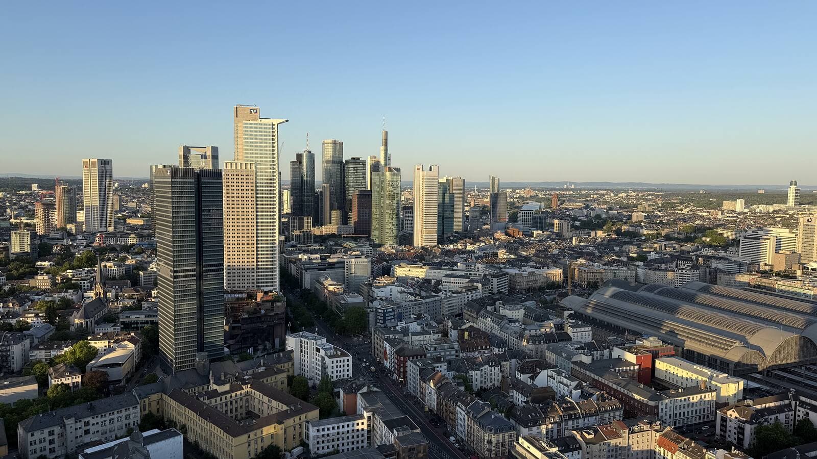 Daylight view across the Frankfurt skyline and the Hauptbahnhof from a high floor of Grand Tower