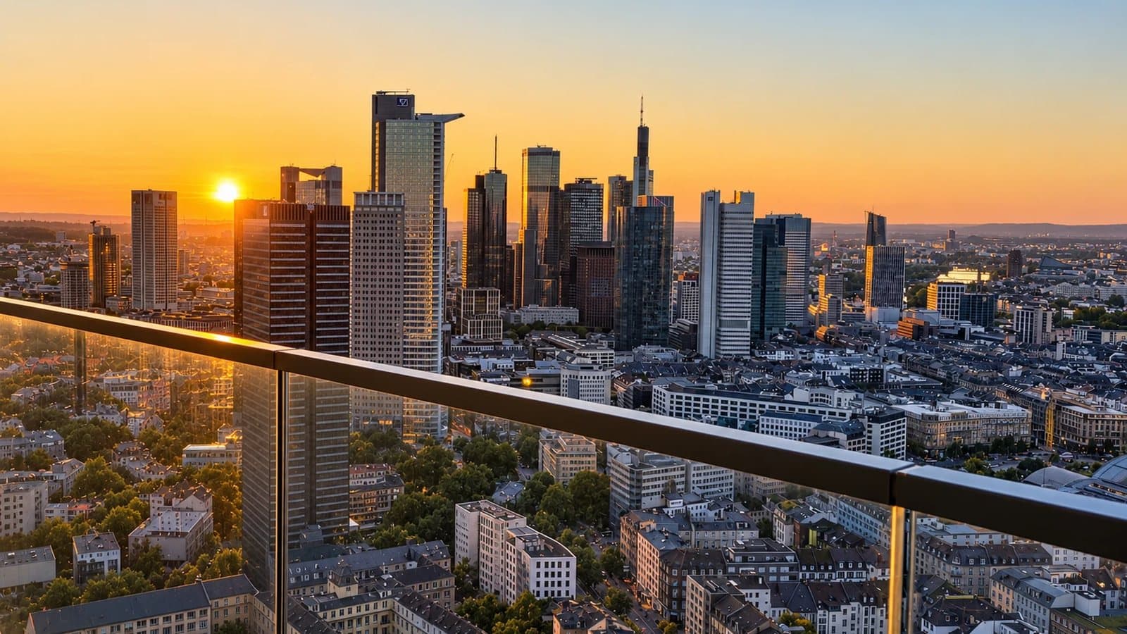The Frankfurt banking district against a low sun, seen from a balcony high up in Grand Tower, the glass balustrade in the foreground