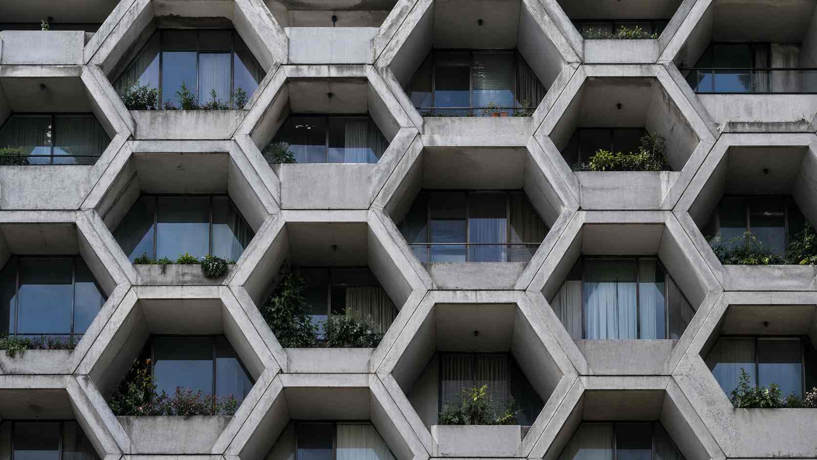 Close-up of a residential tower facade built from stacked precast hexagonal concrete balcony modules