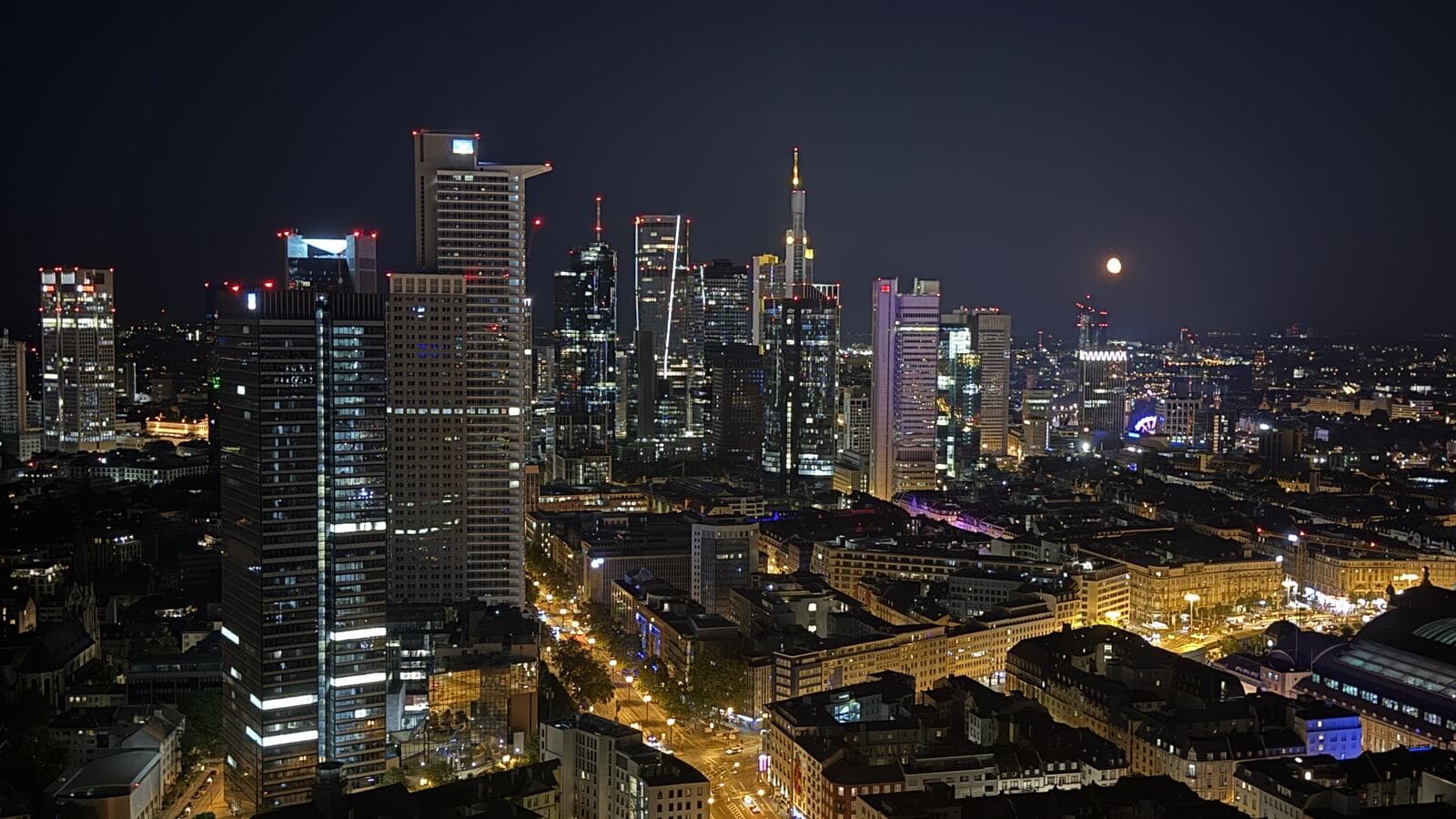 Das Frankfurter Bankenviertel bei Nacht, die beleuchteten Türme der Innenstadt mit aufgehendem Vollmond, gesehen aus der 41. Etage des Grand Tower