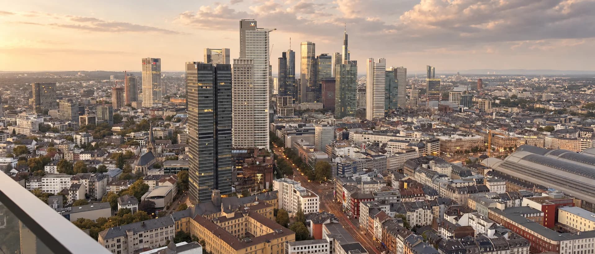 Dusk over the Frankfurt skyline from the wrap-around balcony of the 41st-floor residence, glass balustrade in the foreground