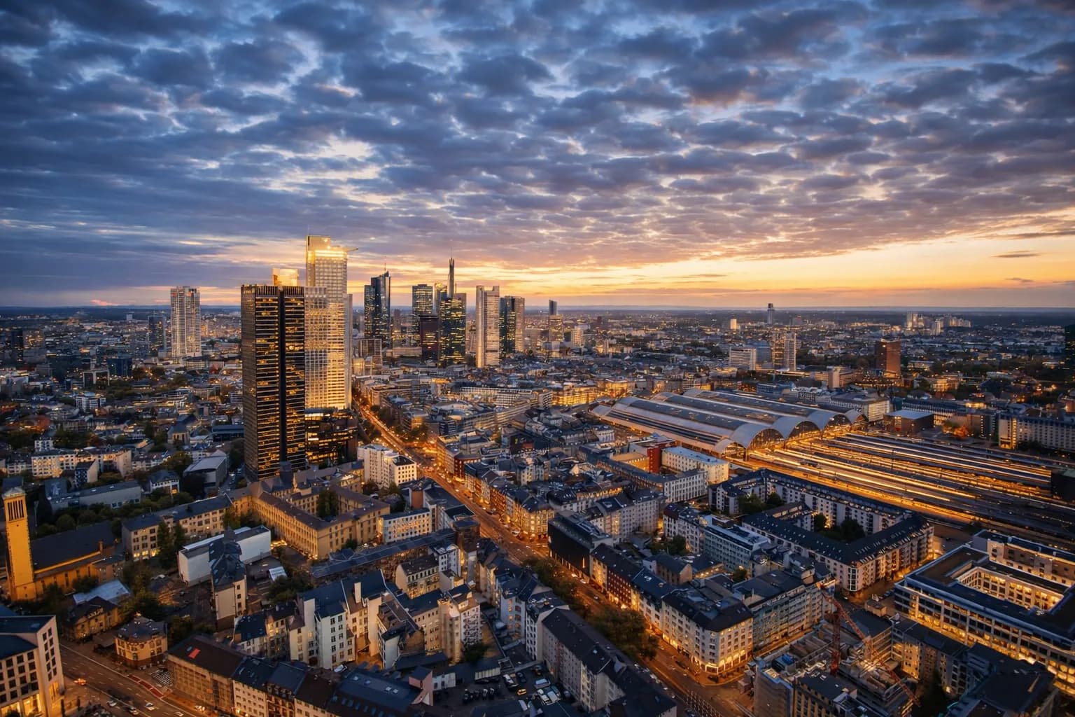 Frankfurt skyline at dusk, seen from the 41st floor of Grand Tower — the financial district and Taunus ridge on the horizon